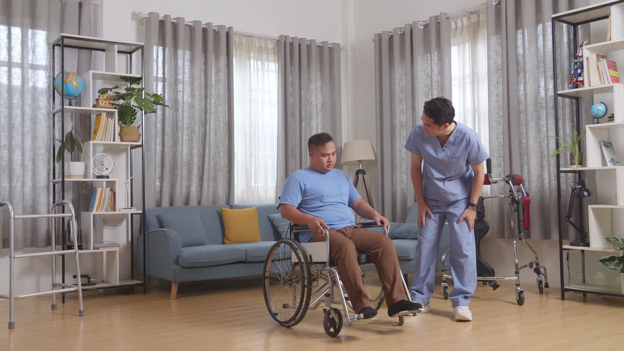 Full Body Of Asian Male Nurse Talking About Medical Test Results And Encouraging A Patient Crying In The Wheelchair After Physical Therapy At Home
