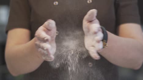 confectioner shakes off flour from hands by clapping