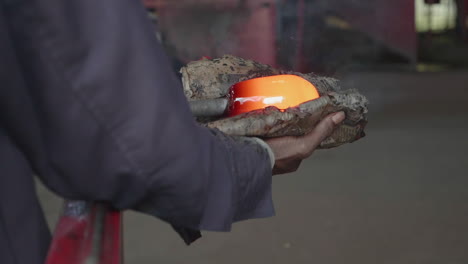 a close up of a man shaping hot glass in a glass blowing factory