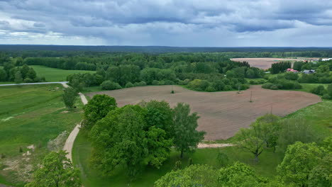Aerial-drone-view-of-a-rural-farm-field-with-a-pond-on-a-cloudy-day