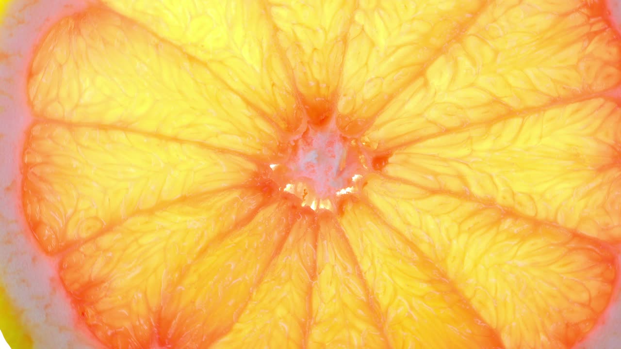 Rotazione dall'alto di una fetta d'arancia su sfondo bianco, fetta trasparente di pompelmo fresco su sfondo bianco, risoluzione 4K
