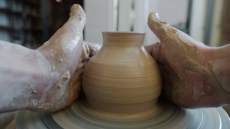 cinemagraph loop of ceramic pot rotating on potter's wheel in dirty hands of craftsman