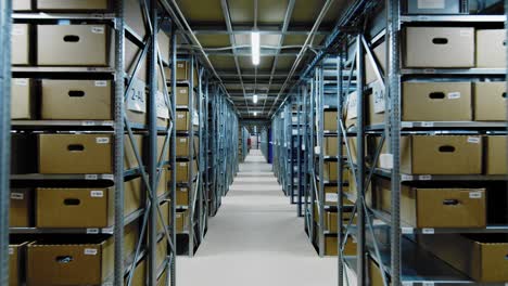 storage facility in big warehouse, racks filled with boxes, dolly in