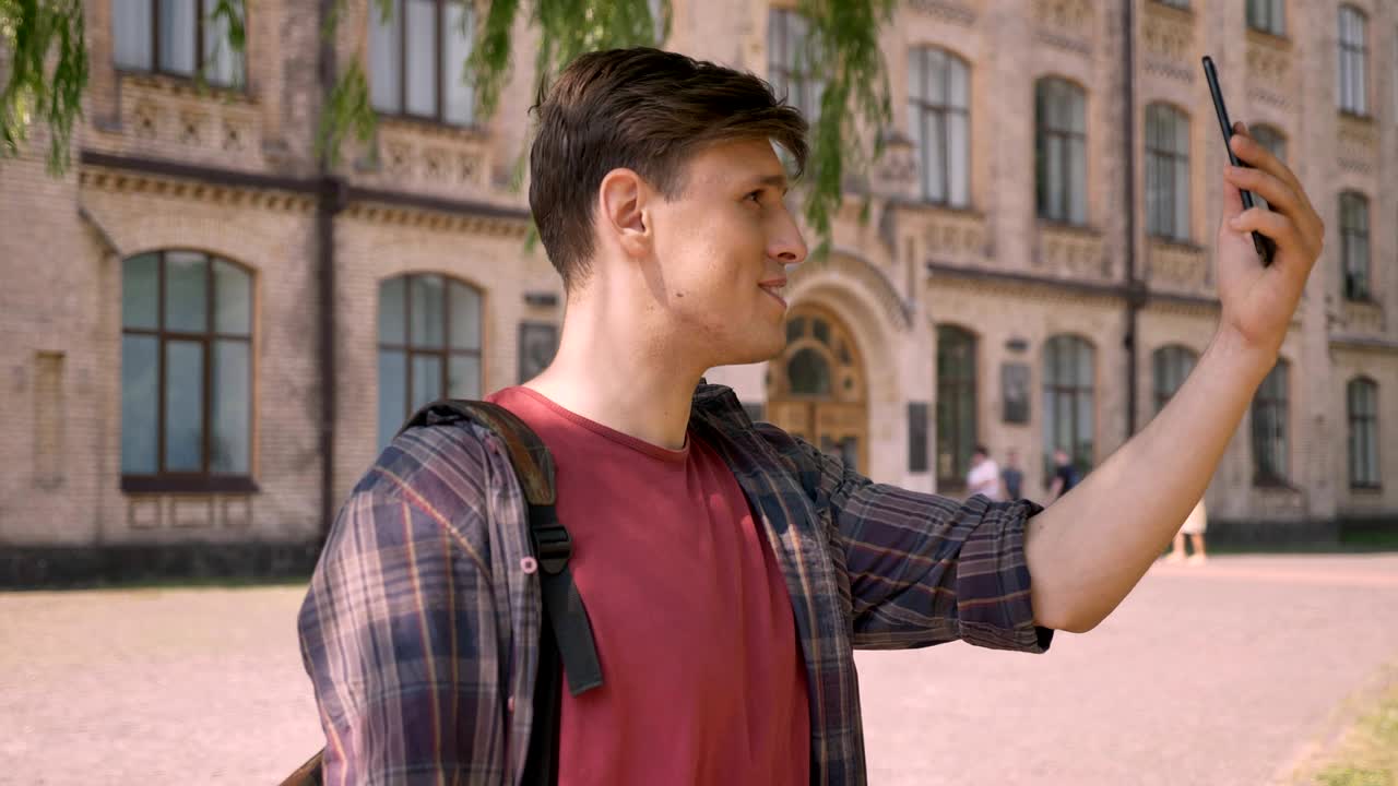 젊은 잘생긴 남자는 스마트폰에서 비디오 채팅에 전화, 손을 흔들고, 낮에 여름에, 의사 소통 개념