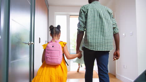 parents at home helping children get ready and leave as family go to school together