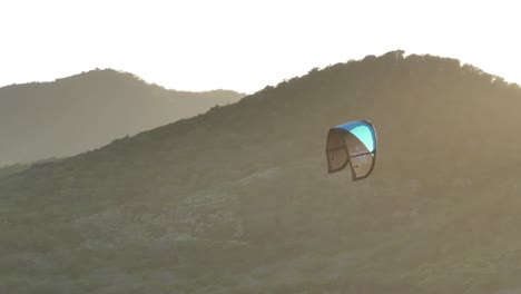 kiteboarding over mountains at sunset