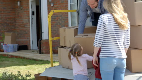 Family Unpacking Moving In Boxes From Removal Truck