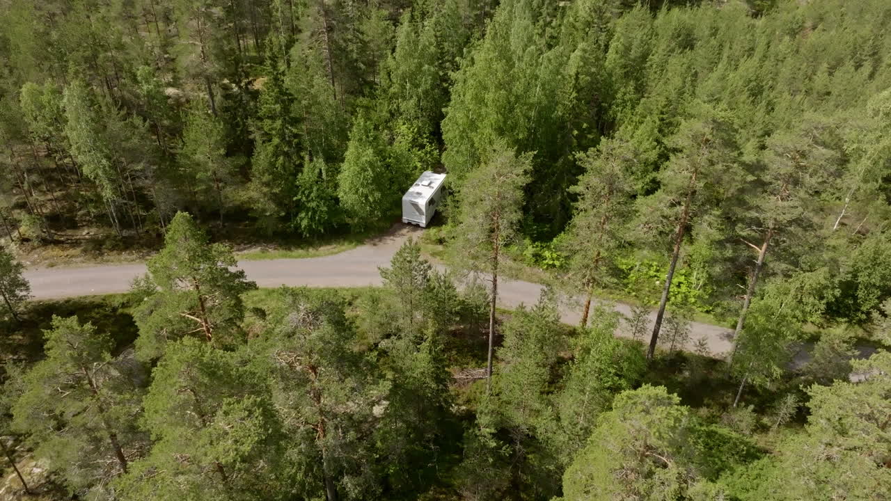 Finlandiya'da bir orman yolunda karavanla doğada kamp yaparken havadan görünüm, yaz günü.