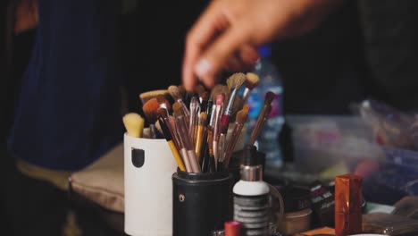 a beautician takes out a makeup brush from the box of makeup kit's collection of brushes