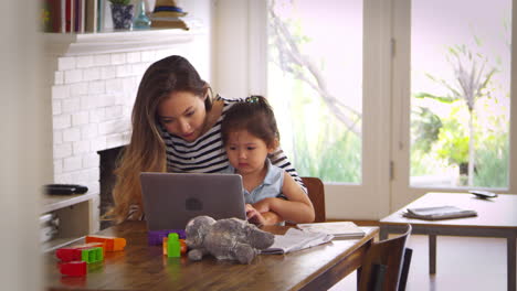 madre e hija ven películas en la computadora portátil en casa juntos