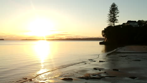 Drohnenaufnahmen,-Während-Sie-über-Den-Strand-Mit-Felsen-Zum-Goldenen-Sonnenaufgang-Fliegen