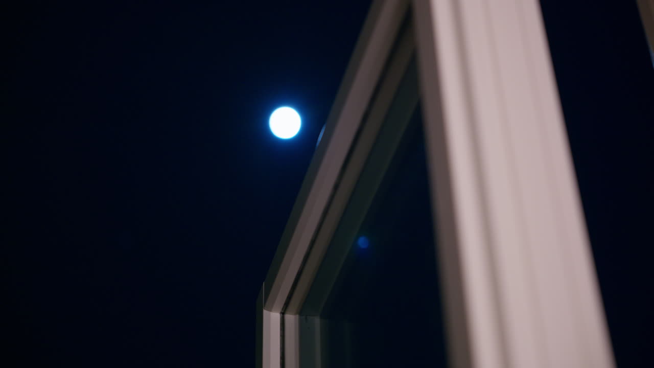 The moon shines bright through the window on a dark cold night
