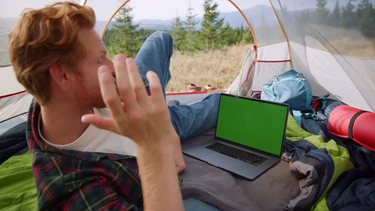 hombre guapo teniendo chat de video en línea en una computadora portátil con pantalla verde en la tienda