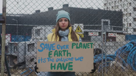 young female activist holding a cardboard placard during a climate change protest while looking at camera 2