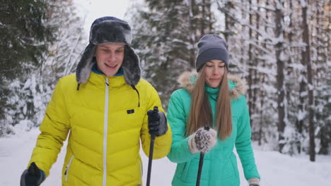 smiling man in a winter jacket skiing in the woods in slow motion with his loving wife. healthy lifestyle. young couple