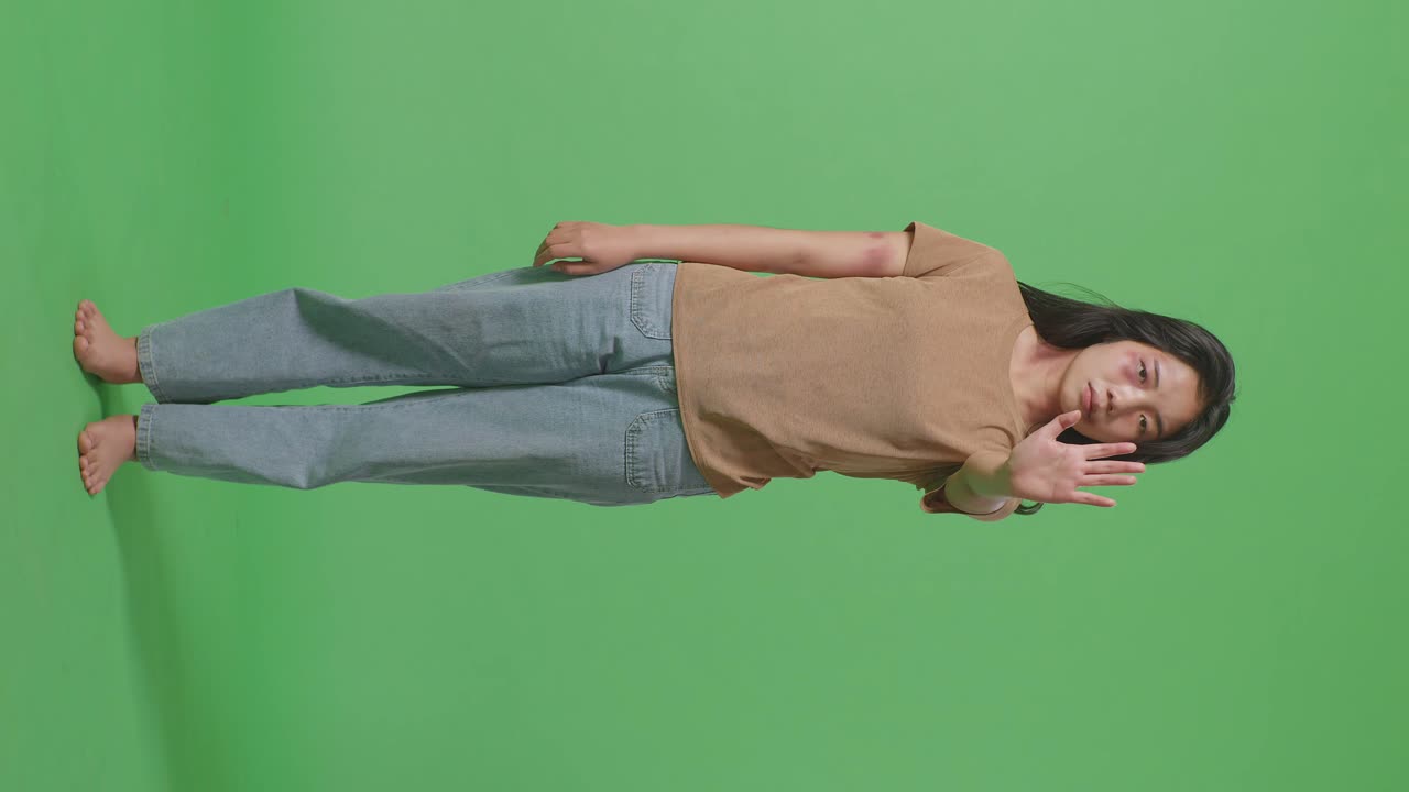 몸에 이 있는 젊은 아시아 여성의 몸이 카메라를 바라보고 녹색 스크린 배경 스튜디오에서 폭력을 멈추기 위해 손 표시를 보여줍니다.