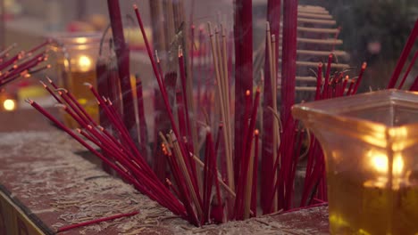 de cerca manos encendiendo incienso rojo chino oración palos fuego y humo en el interior del templo de china