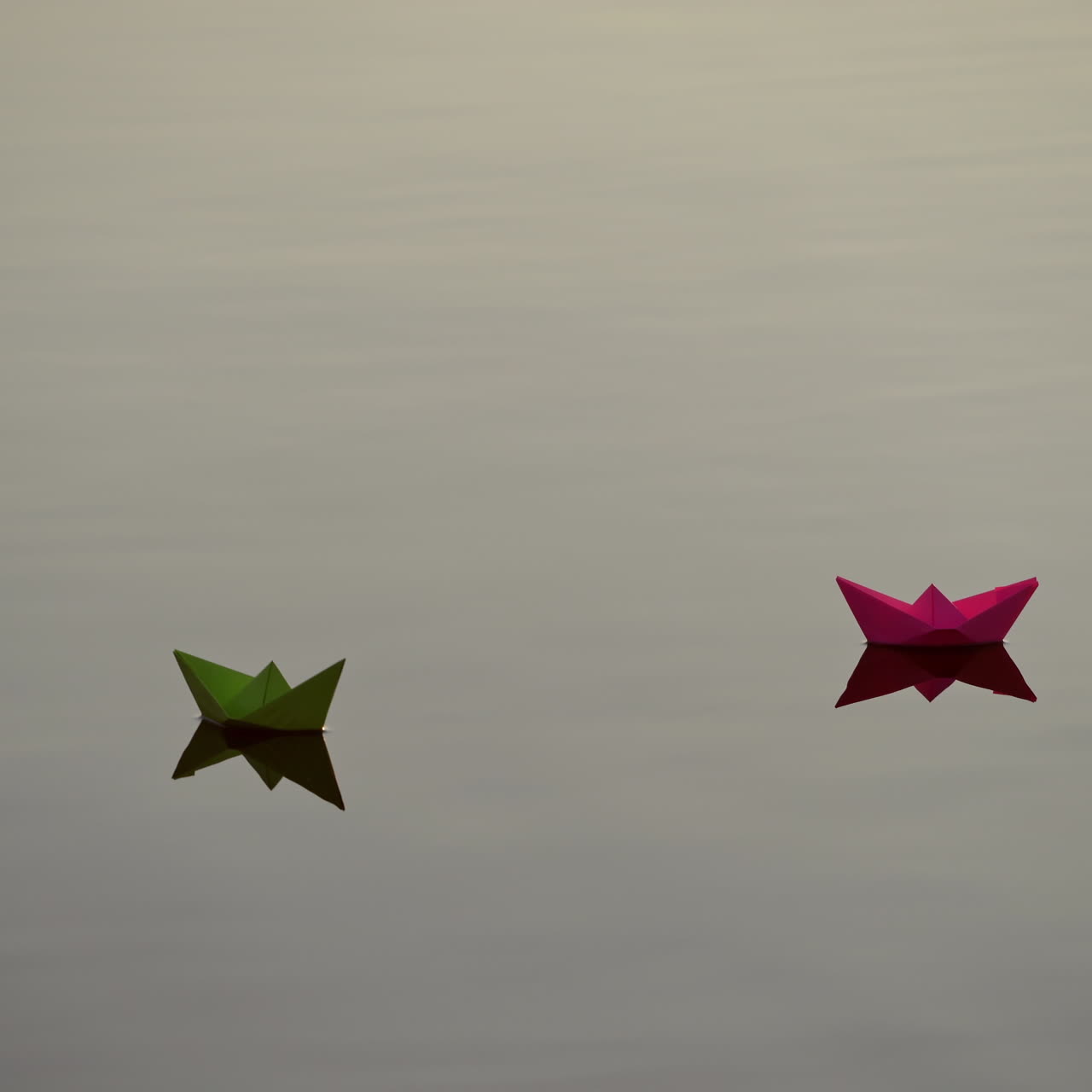 Beautiful paper boats floating. Two colorful origami ships swimming with their reflection in water. Freedom and hope concept.