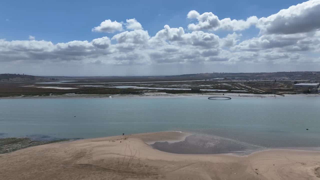 Smooth cinematic shot of the Loukkos River next to the archaeological site of Lixus, showcasing calm waters, natural scenery, and the historic riverside setting