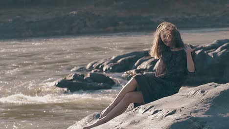 fair haired girl fixes tight dress on huge rock slow motion