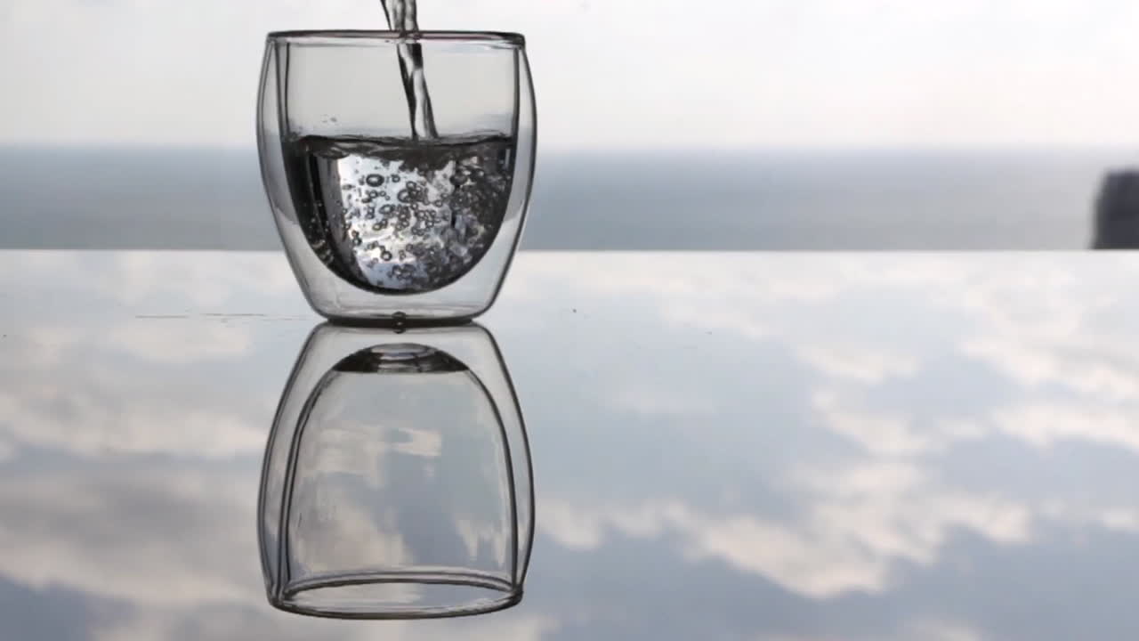 cinemagraph de agua llenando el vaso mientras no pasa nada en su reflejo