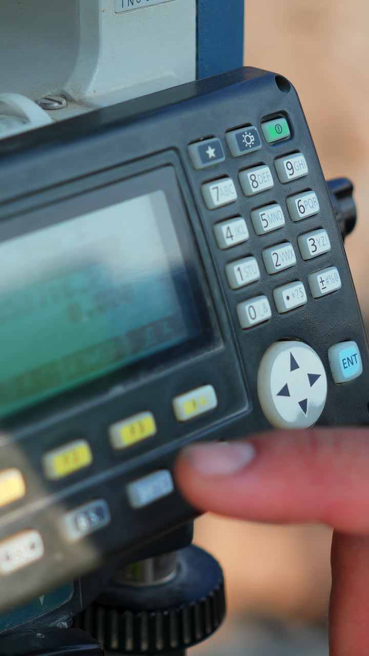 Close-up of a Total Station with Hand Operating the Keypad