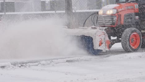 municipal service worker operating snow clearing truck with broom, removing snow from street during blizzard snow storm