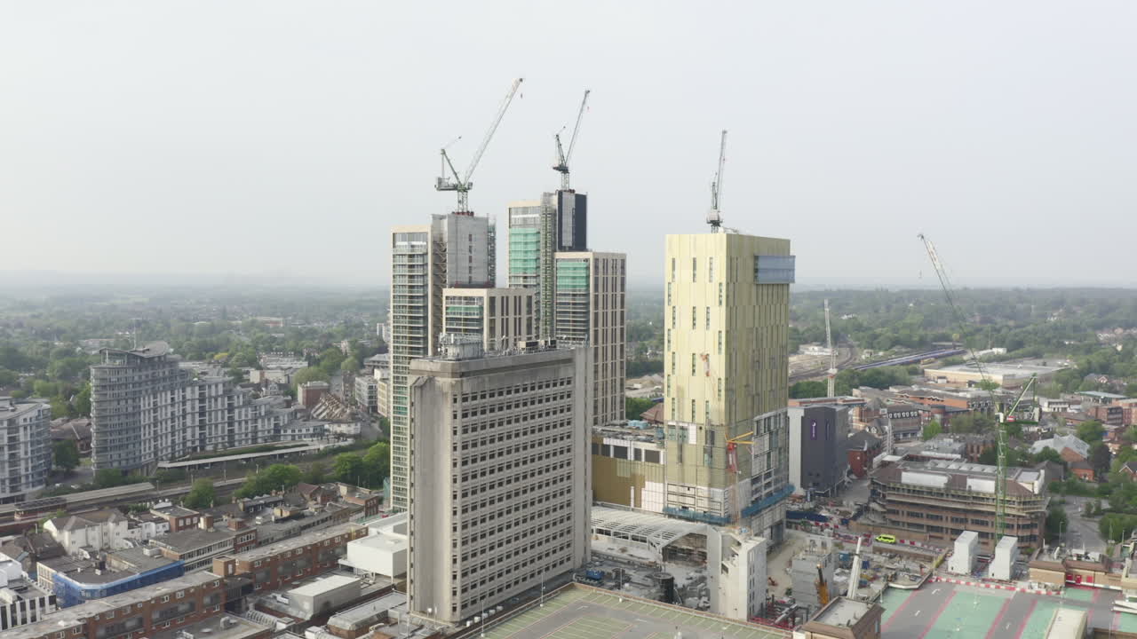 toma aérea de drones del paisaje urbano de woking, una ciudad en inglaterra con rascacielos de gran altura y obras de construcción de grúas con rastreo de drones acercándose