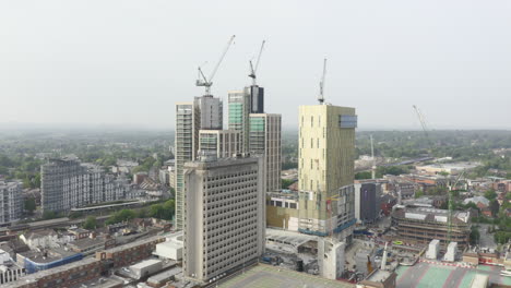 toma aérea de drones del paisaje urbano de woking, una ciudad en inglaterra con rascacielos de gran altura y obras de construcción de grúas con rastreo de drones acercándose