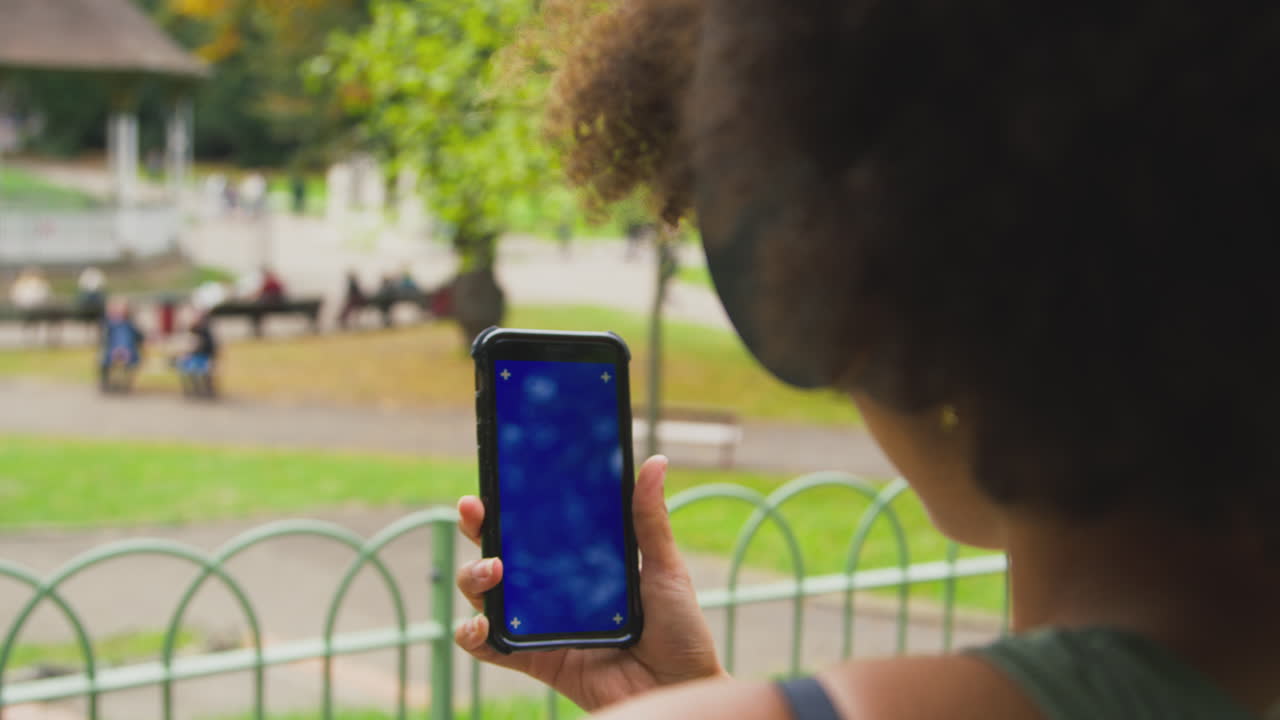 primer plano de una mujer al aire libre con auriculares inalámbricos transmitiendo programas o música desde un teléfono móvil