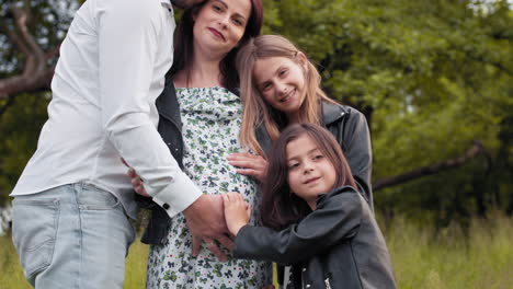 family portrait of a pregnant mother and children in a park