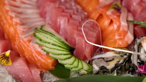 a detailed view of fresh salmon, tuna, and oysters garnished with cucumber and edible flowers.
