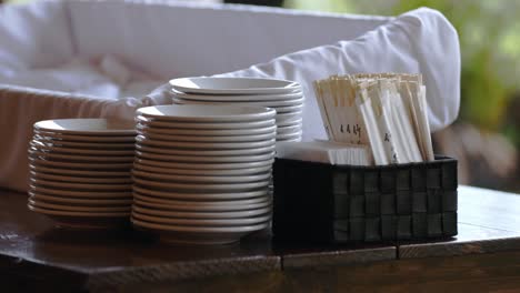 pilas de platos blancos, palillos de madera desechables y servilletes dispuestos para un buffet