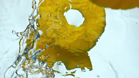 yellow sliced pineapple splashing water close up. juicy ananas falling in liquid