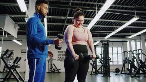 personal trainer assisting woman with dumbbell exercises