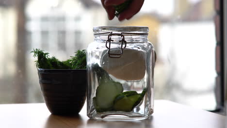 filling glass jar with fresh vegetables for marinade cooking