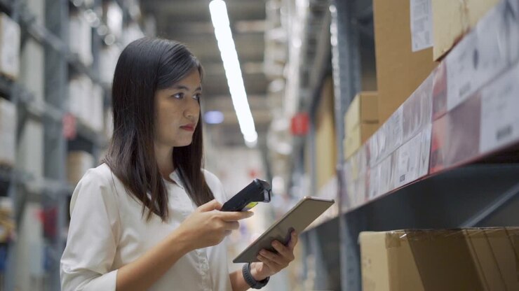 Female worker scanning products with barcode scanner in warehouse.
