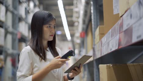 female worker scanning products with barcode scanner in warehouse.