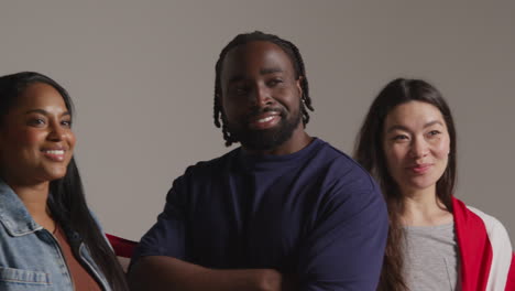 studio portrait shot of multi-cultural group of friends holding american flag behind them celebrating 4th july independence day