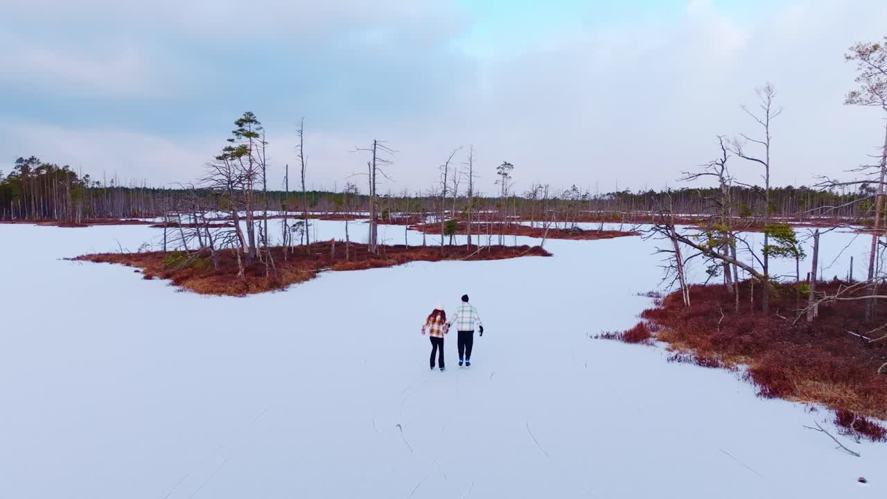Romantic couple glides across frozen bog lake in slow motion, peaceful winter