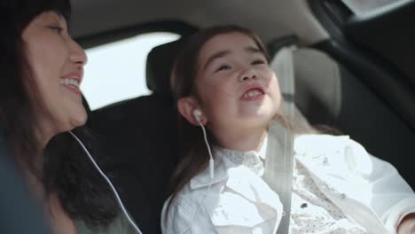 little girl and mother singing in car