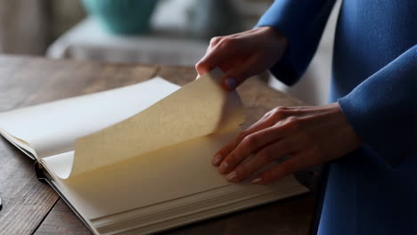 person turning pages of a book on a wooden table