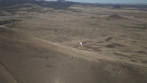 paraglider in flight over desert landscape near flagstaff in arizona, usa. orbiting drone shot