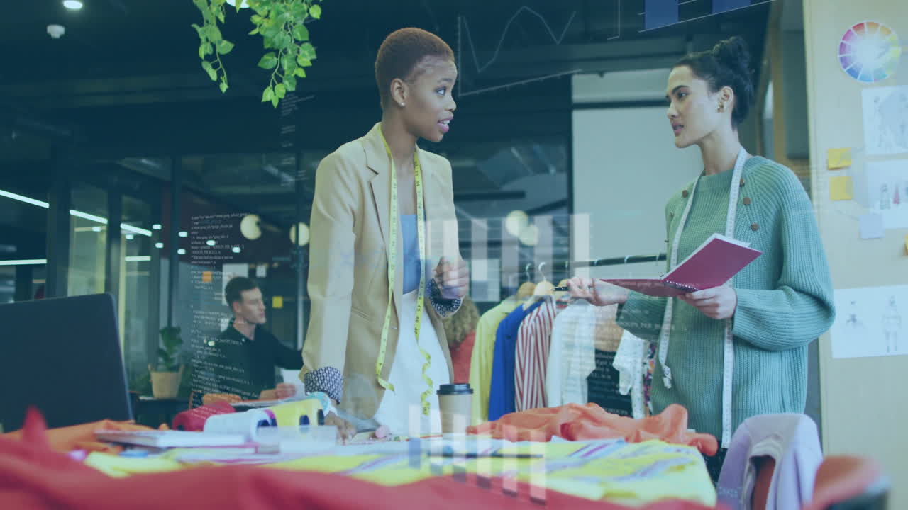 Two women discussing fashion designs in modern office with data animation overlay
