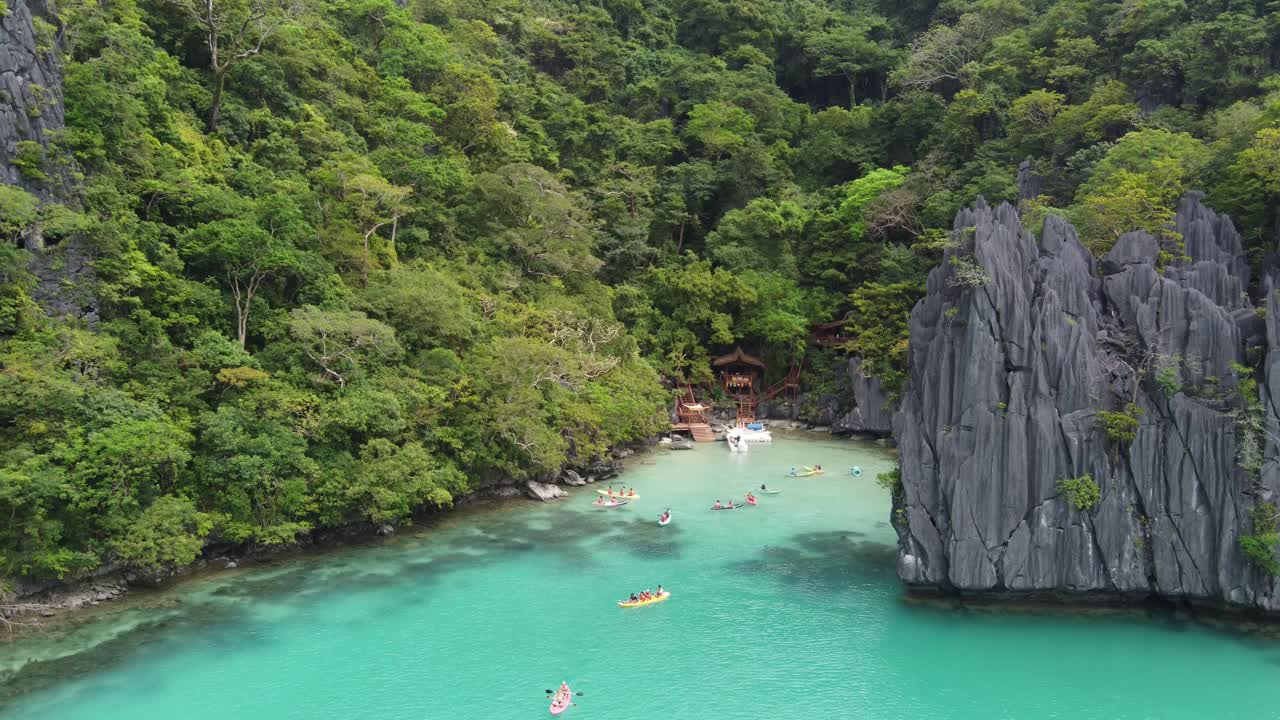 Turistas en kayak en la cristalina laguna de Cadlao, en el exótico paisaje de formaciones kársticas e islas de El Nido, Palawan.