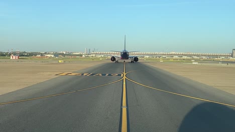 vista externa tomada desde una cabina de piloto de un avión que se desplaza hacia adelante en una soleada mañana de verano, con la silueta del avión en la vía de rodaje