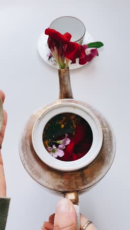 la mano de la mujer abriendo una olla de té vintage con flores