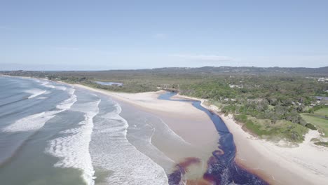 riachuelo de bebel con agua marrón que fluye hacia el mar - playa de bebel en nueva gales del sur, australia