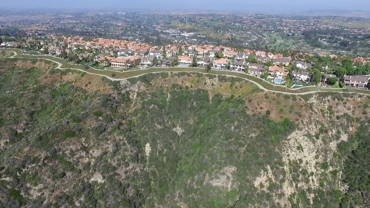 Slow aerial drone flying back from luxury homes in Laguna Niguel, Orange County, California showcasing hills