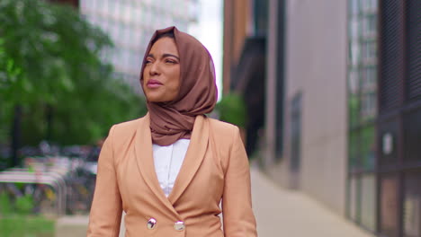 close up of modern muslim businesswoman wearing hijab with business suit walking to work past office buildings